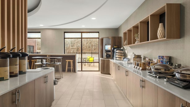 A modern kitchen with wooden cabinets, a central island, and a view to a balcony. - Springhill Suites by Marriott Morgantown (Morgantown)