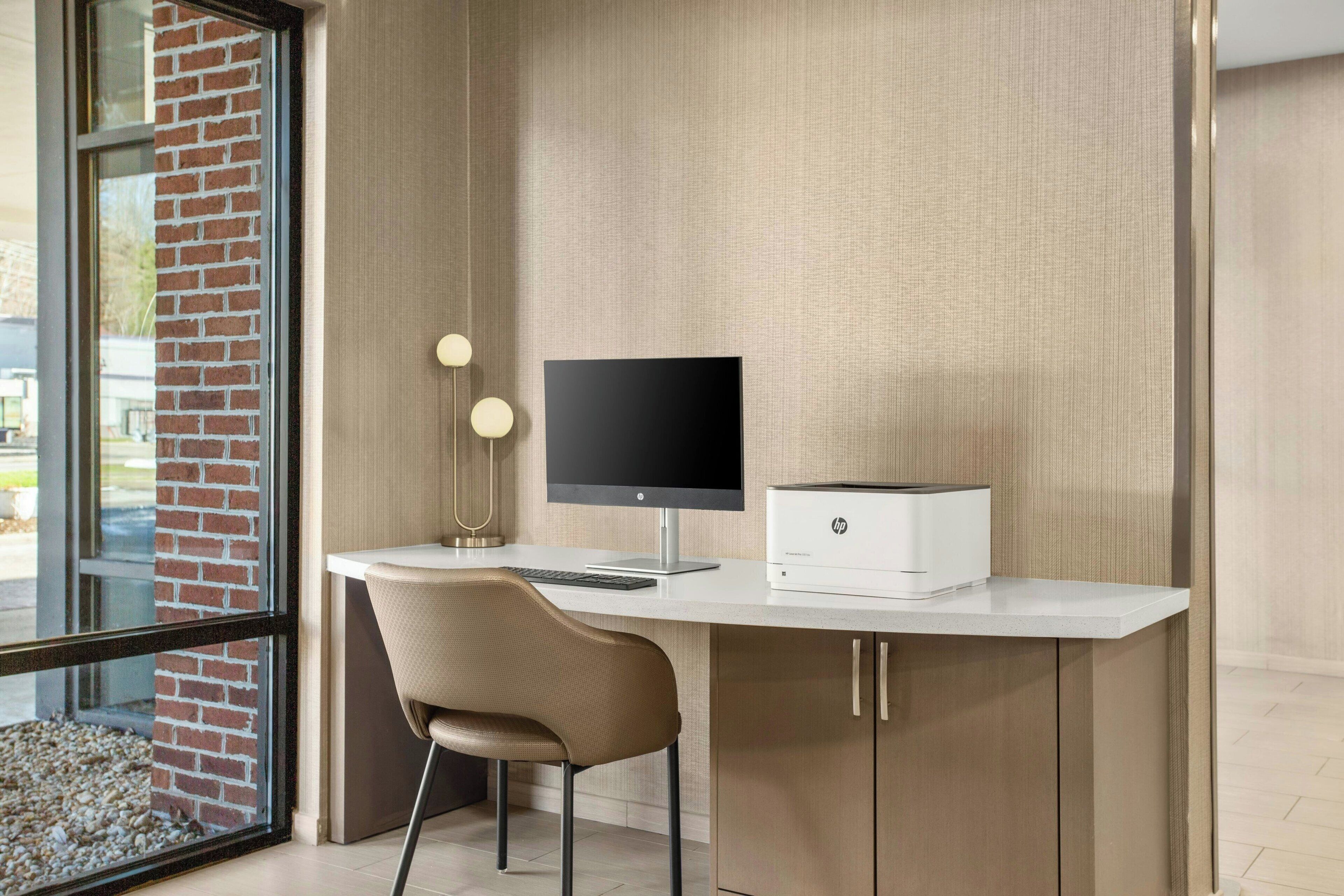 Un escritorio moderno con una computadora, una silla e impresora.