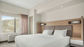 A large bed with a headboard, a window with curtains, and a radiator. - Springhill Suites by Marriott Morgantown (Morgantown)