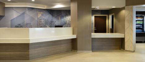 A modern reception area with a counter, a wall with text, and a vending machine.