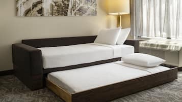 Una cama doble con estructura de madera y ropa de cama blanca, una mesita de noche, una lámpara y un cuadro abstracto grande en la pared.