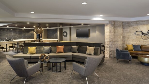 A modern living room with a sectional sofa, two armchairs, a coffee table, and a dining area with a bar. - SpringHill Suites by Marriott Fort Worth University (Fort Worth)