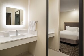 A hotel bathroom with a sink, mirror, and towel rack.