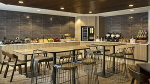 A modern restaurant with a central bar area, multiple seating options, and a variety of food and beverage dispensers. - SpringHill Suites by Marriott Fort Worth University (Fort Worth)