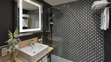 Un baño moderno con un espejo grande, un lavabo y una zona de ducha.