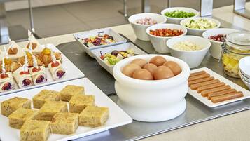 Una mesa de buffet con diferentes alimentos, como pasteles, huevos y verduras.