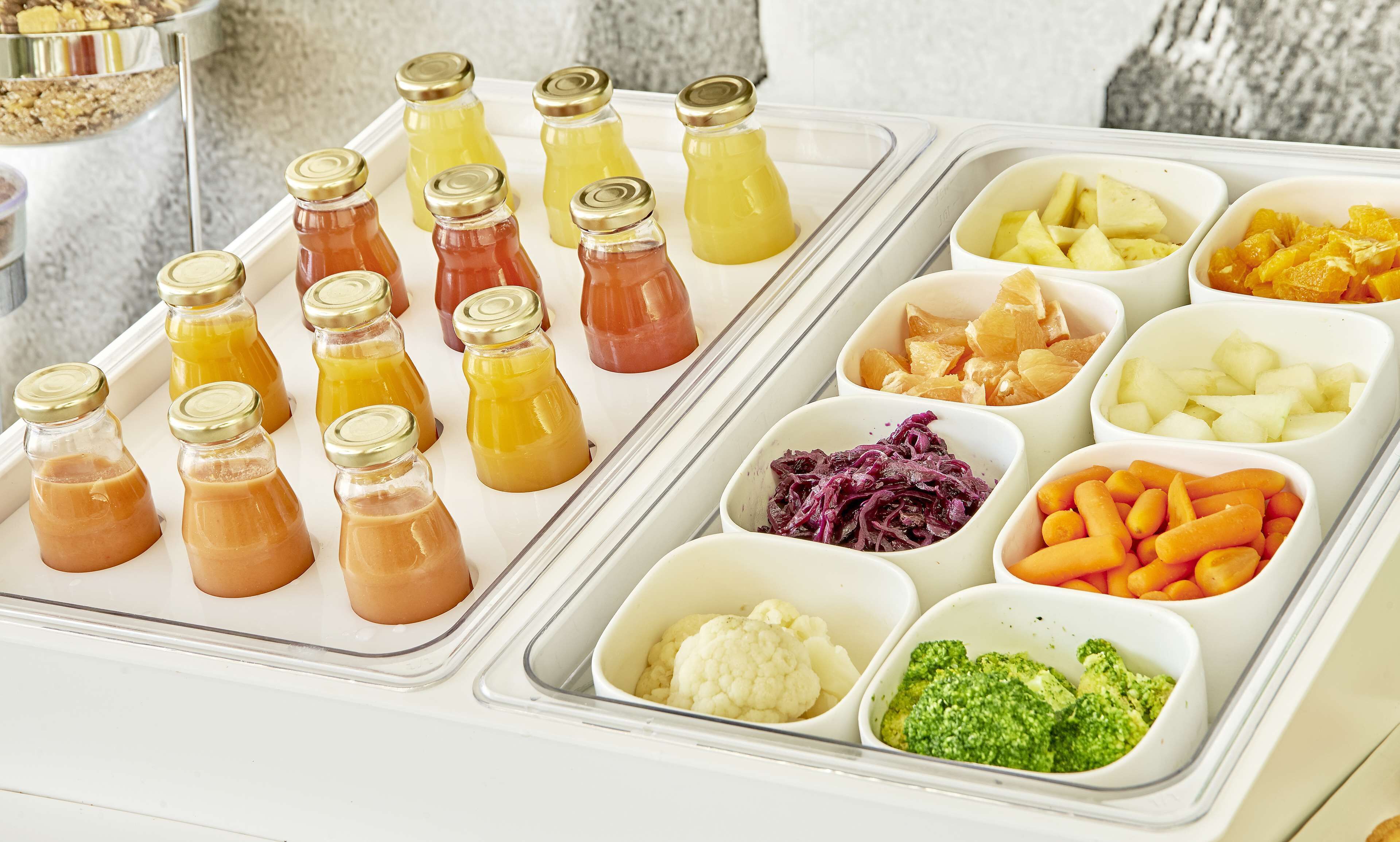 A food buffet with various drinks and vegetables.
