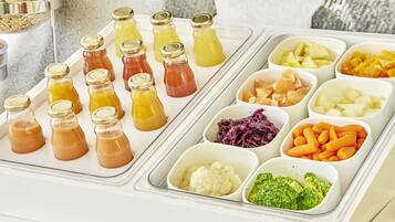 A food buffet with various drinks and vegetables.