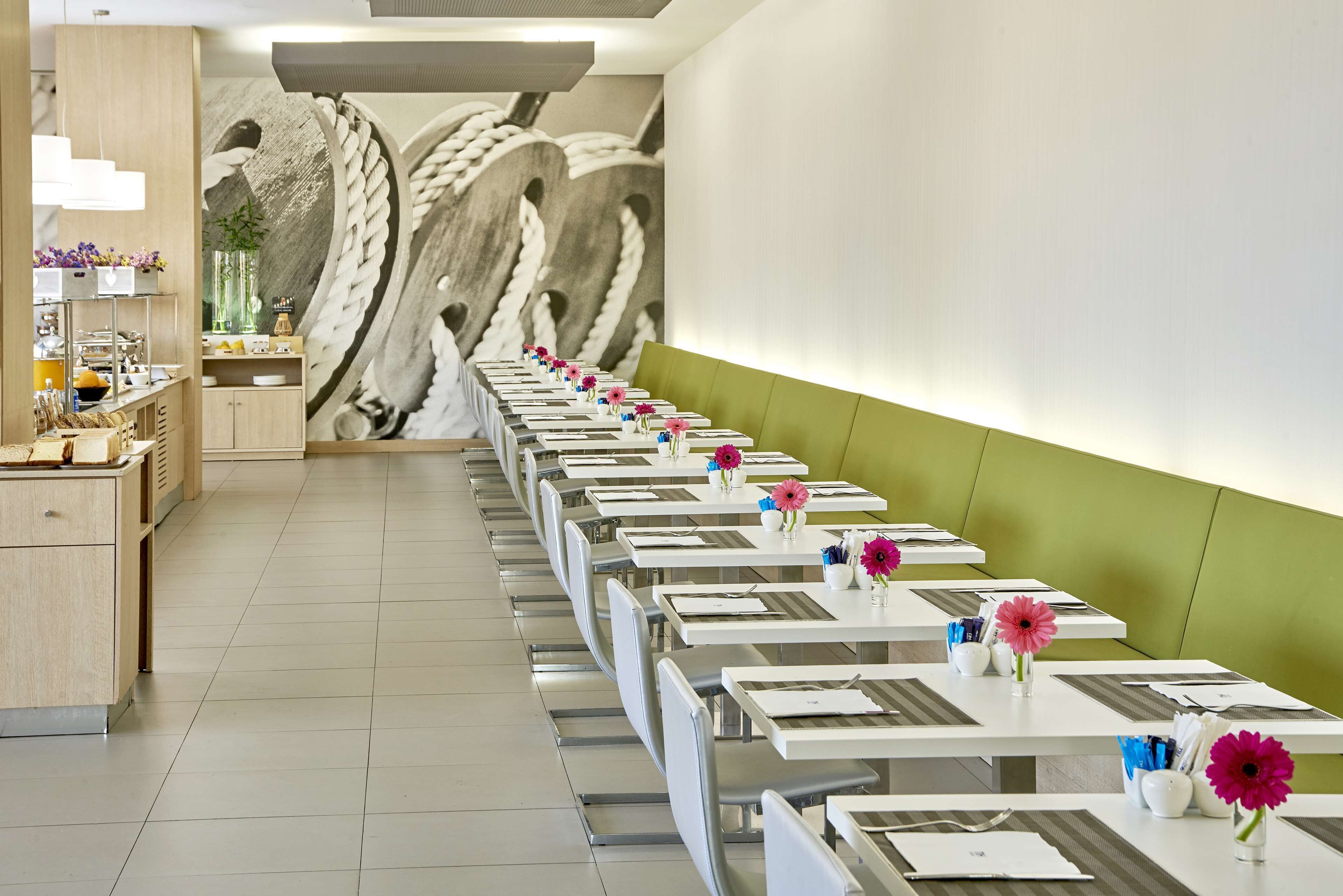 A long dining table with chairs, a green wall, and a mural of a bird in flight.