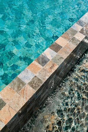 Une piscine à l’eau claire, dont les bords sont recouverts de carreaux.