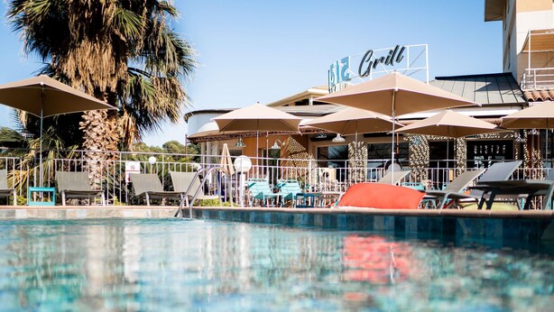 A pool area with lounge chairs, umbrellas, and a sign for a Grill restaurant. - Ibis La Ciotat (La Ciotat)