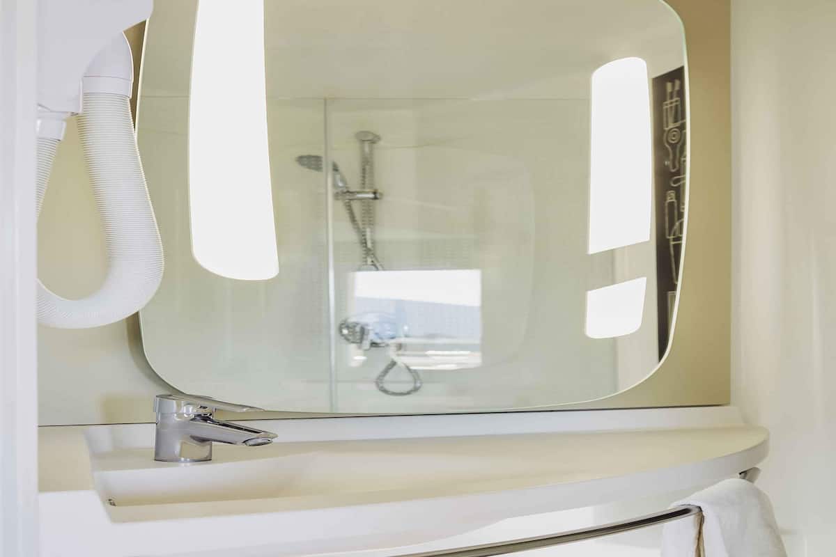 Ein Badezimmer mit einem großen Spiegel, einem Waschbecken und einer Dusche.