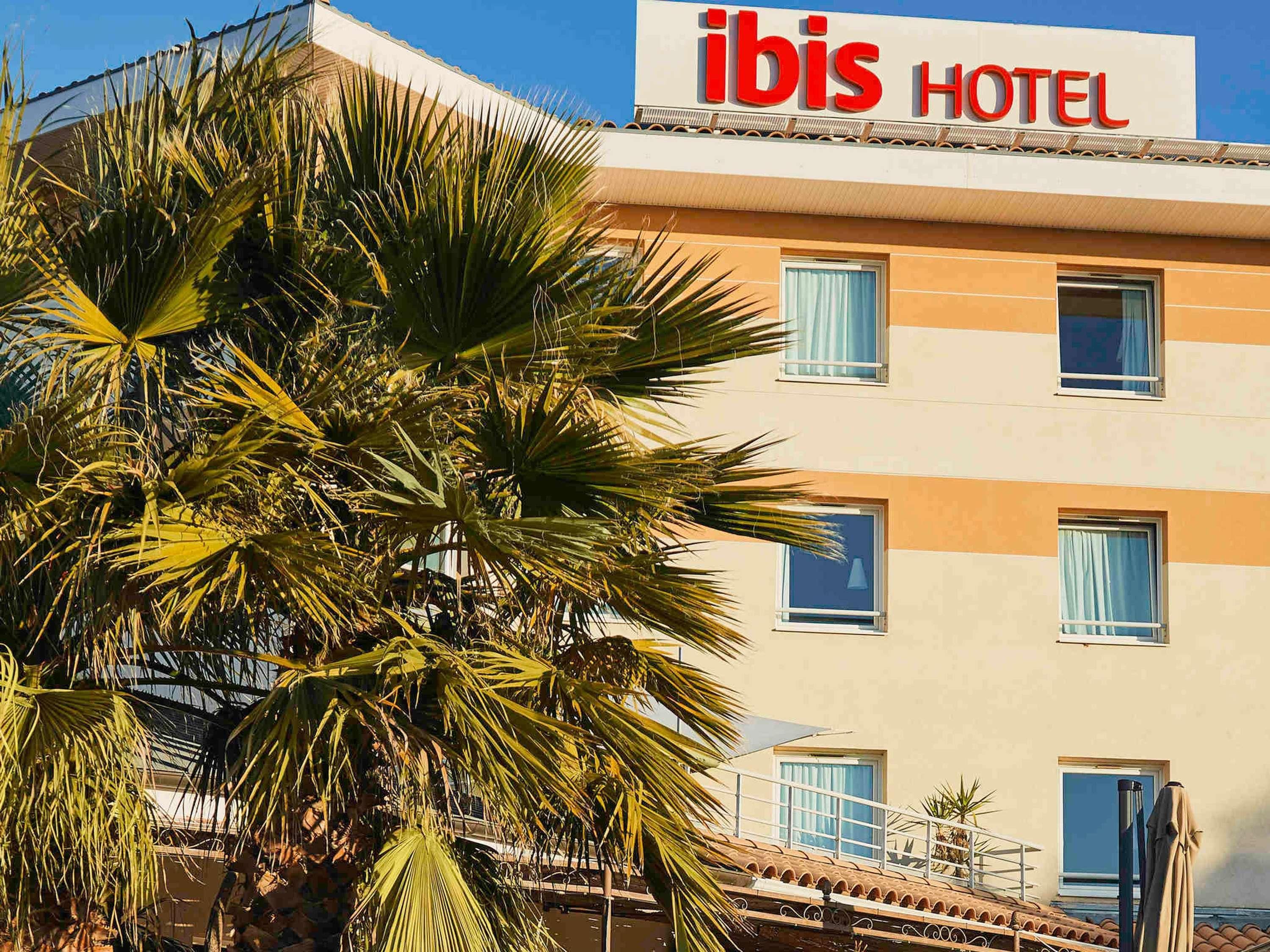 Un edificio de hotel con un letrero que dice 'ibis HOTEL' y varias ventanas.