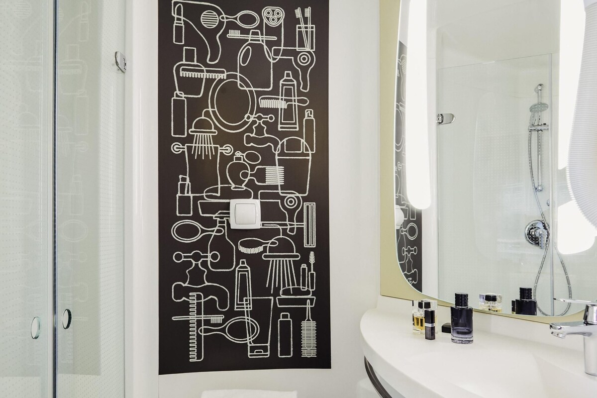 A bathroom with a large mirror, a white sink, and a towel rack.