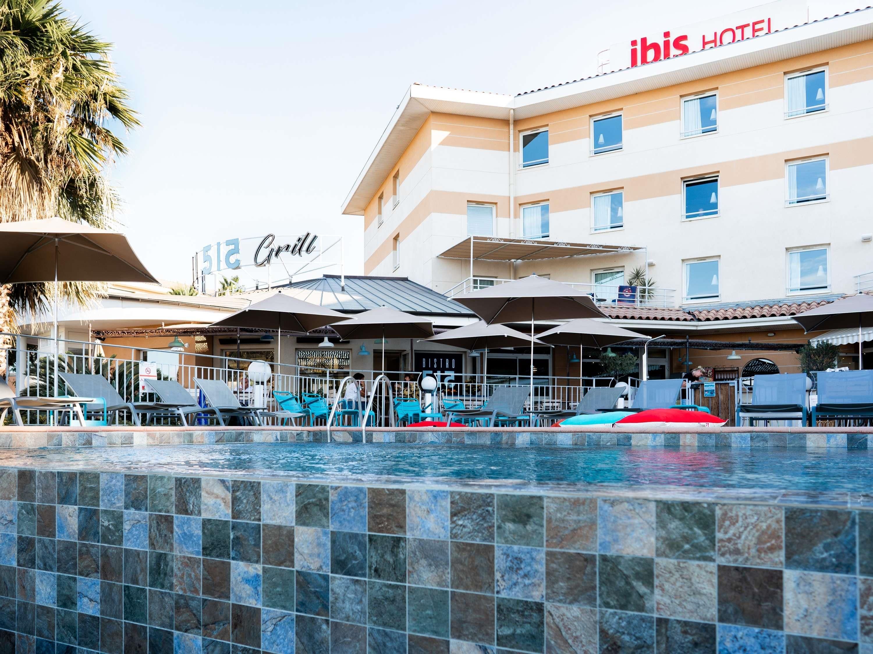 Een hotel met een zwembad, terras en een bordje met de tekst 'ibis Hotel'.
