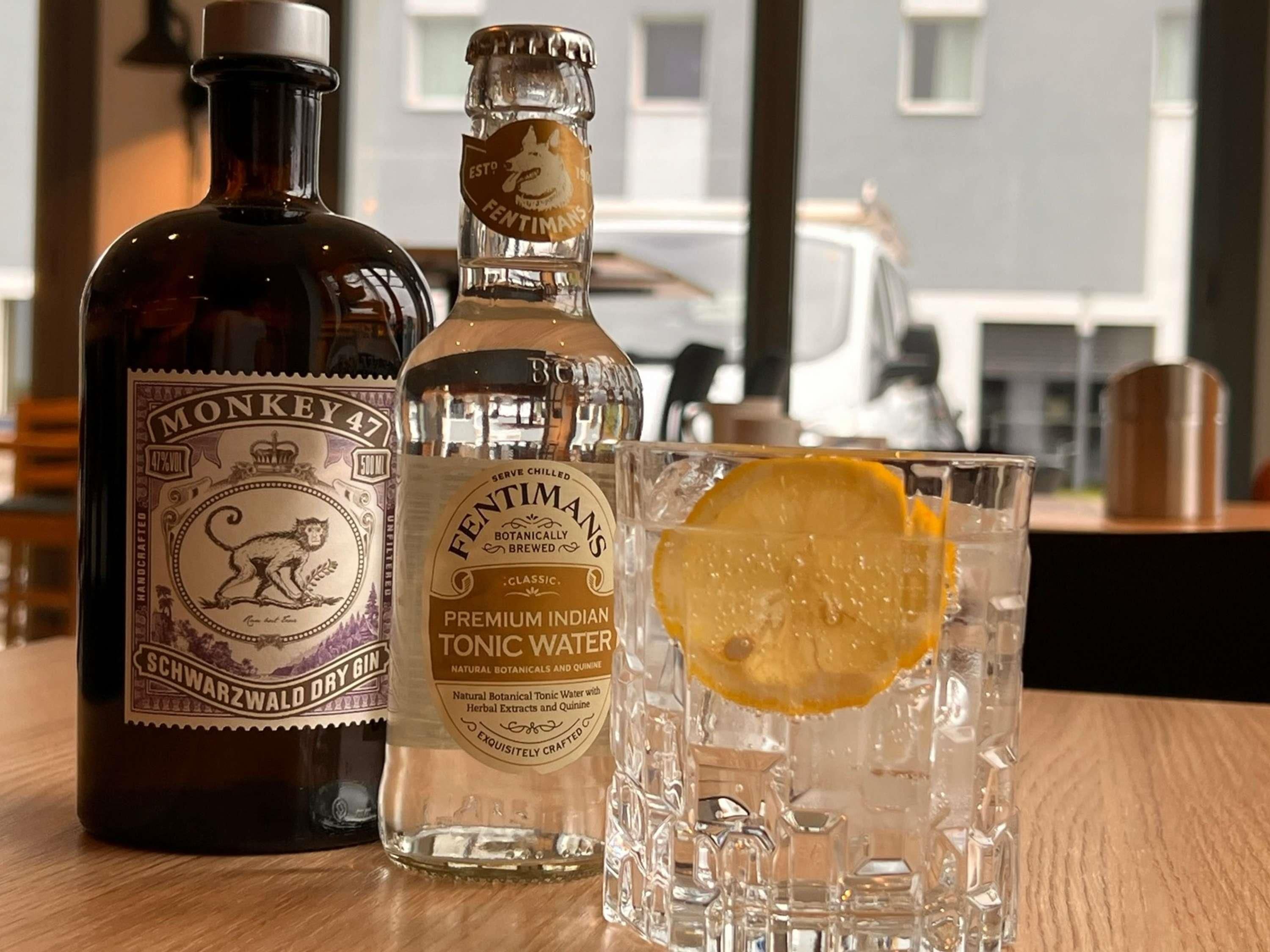 Una bottiglia di gin Monkey 47, una bottiglia di acqua tonica Fentimans e un bicchiere con una fetta di limone.