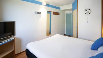 Une chambre d’hôtel avec un lit, un téléviseur posé sur un meuble, une porte et une horloge murale.