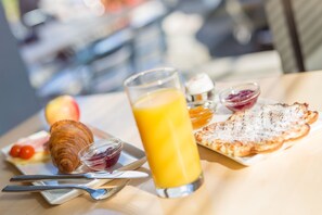 Een ontbijt met croissants, fruit, een glas sinaasappelsap en een bord toast.