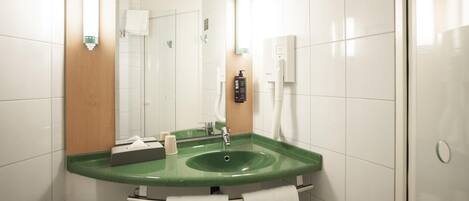 Un baño con un lavamanos verde, azulejos blancos, un espejo y un perchero para toallas.