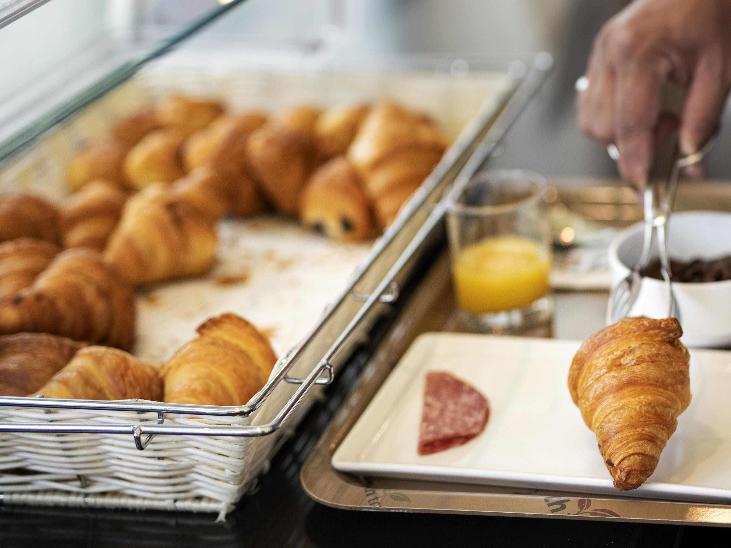 A breakfast buffet with croissants and a glass of orange juice.