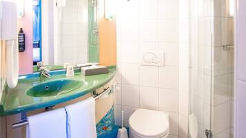 Un baño con un lavamanos verde, un inodoro blanco y una zona de ducha.