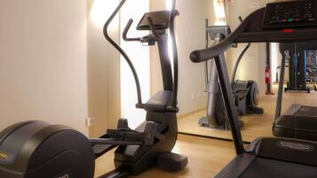 Un gimnasio con equipo de ejercicio, incluyendo una caminadora, elíptica y bicicleta estática.