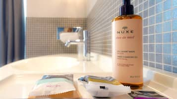 Ein Badezimmer mit Waschbecken, einer Flasche NUXE Handreinigungsgel und zwei Toilettenartikeln vom Hotel Mercure.