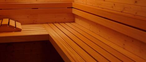 A sauna with wooden benches and a bench with a towel.