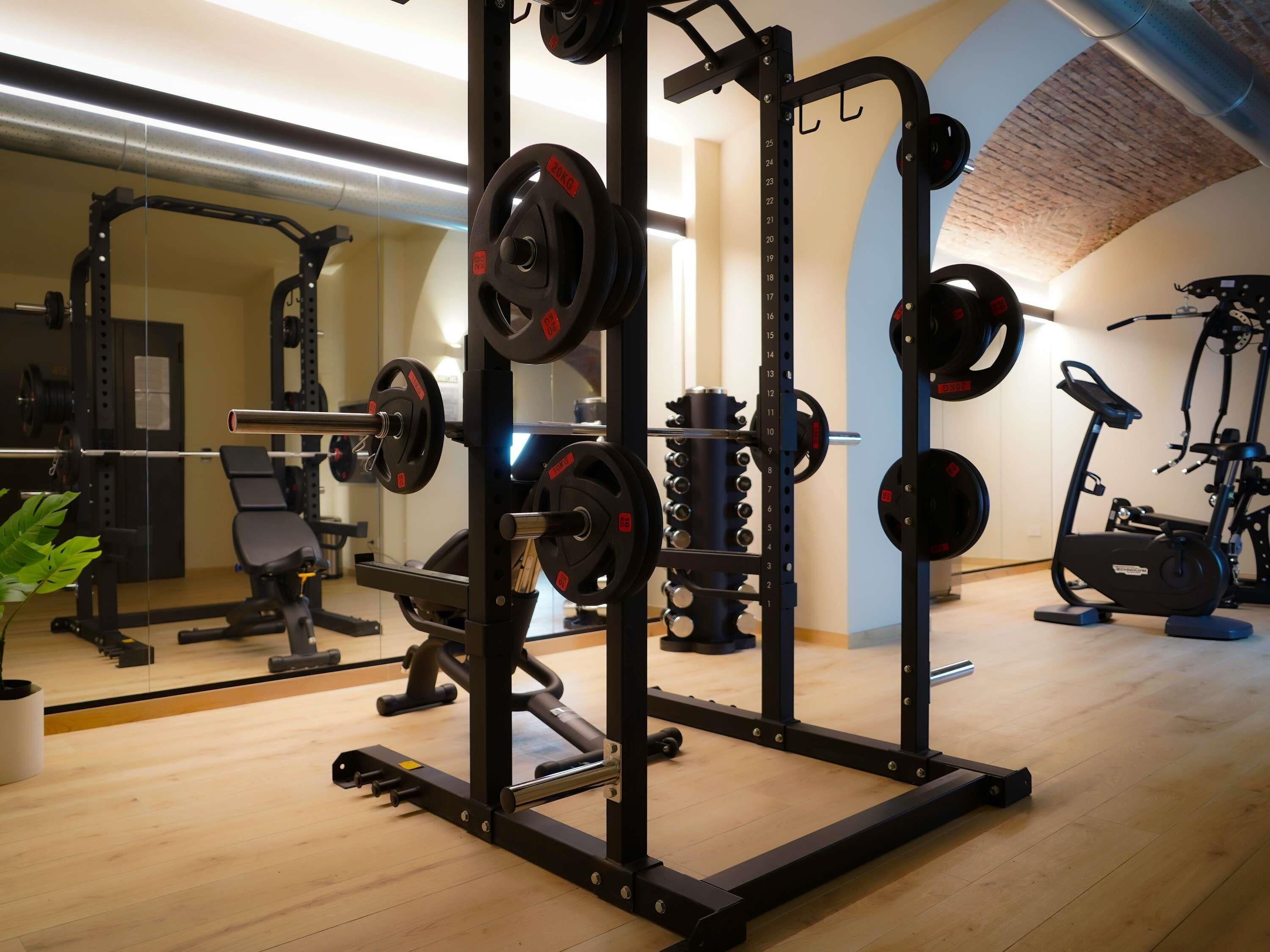 Une salle de sport équipée de matériel de musculation, de vélos d’exercice et d’un miroir.
