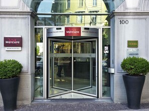Ingresso con porta girevole di un hotel, con insegne che riportano 'Mercure Bergamo Palazzo Dolci' e 'Albergo Hotel'.