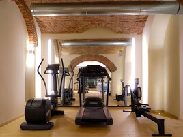 Una palestra con tapis roulant, cyclette ellittiche e vogatore, caratterizzata da mattoni a vista e pavimento in legno.