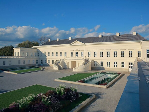 A large, symmetrical building with a central staircase, multiple windows, and a well-maintained lawn.