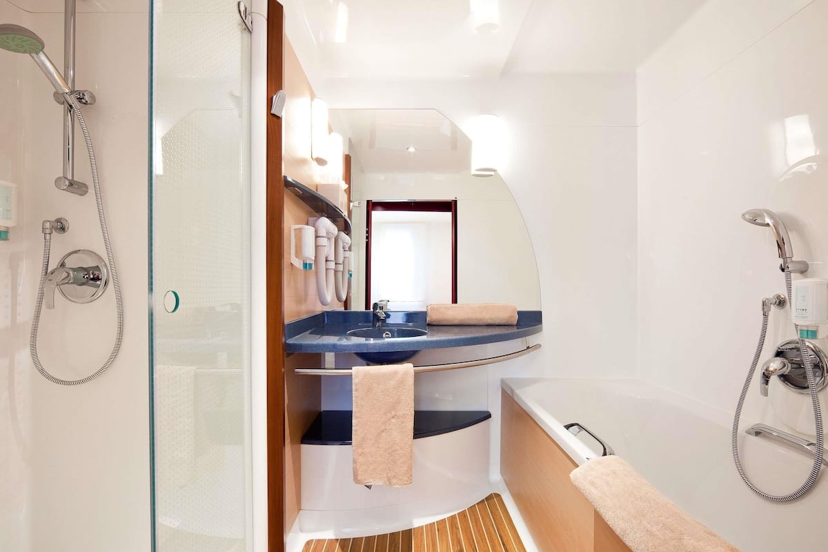 A compact bathroom with a shower, a sink, and a mirror.