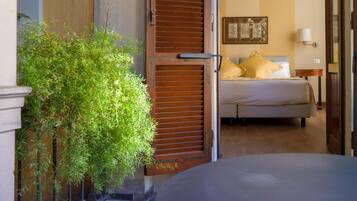 A hotel room with a bed, a nightstand, a lamp, and a window with blinds.
