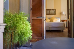 Una camera d'albergo con un letto, un comodino, una lampada e una finestra con persiane.