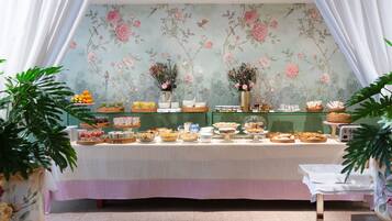 A buffet table with various food items and a floral wallpaper background.