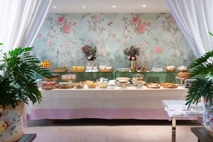 Un tavolo da buffet con diversi cibi e uno sfondo decorato con carta da parati floreale.