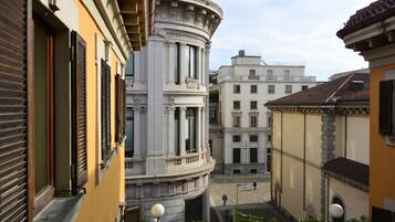 Eine enge Straße mit historischen Gebäuden, darunter ein markantes weißes Gebäude mit Säulen und ein gelbes Gebäude mit Fensterläden.