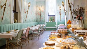 A dining area with tables set for a meal, a variety of desserts displayed, and a view of the outdoors through a window. - Hotel Gran Duca Di York (Milan)