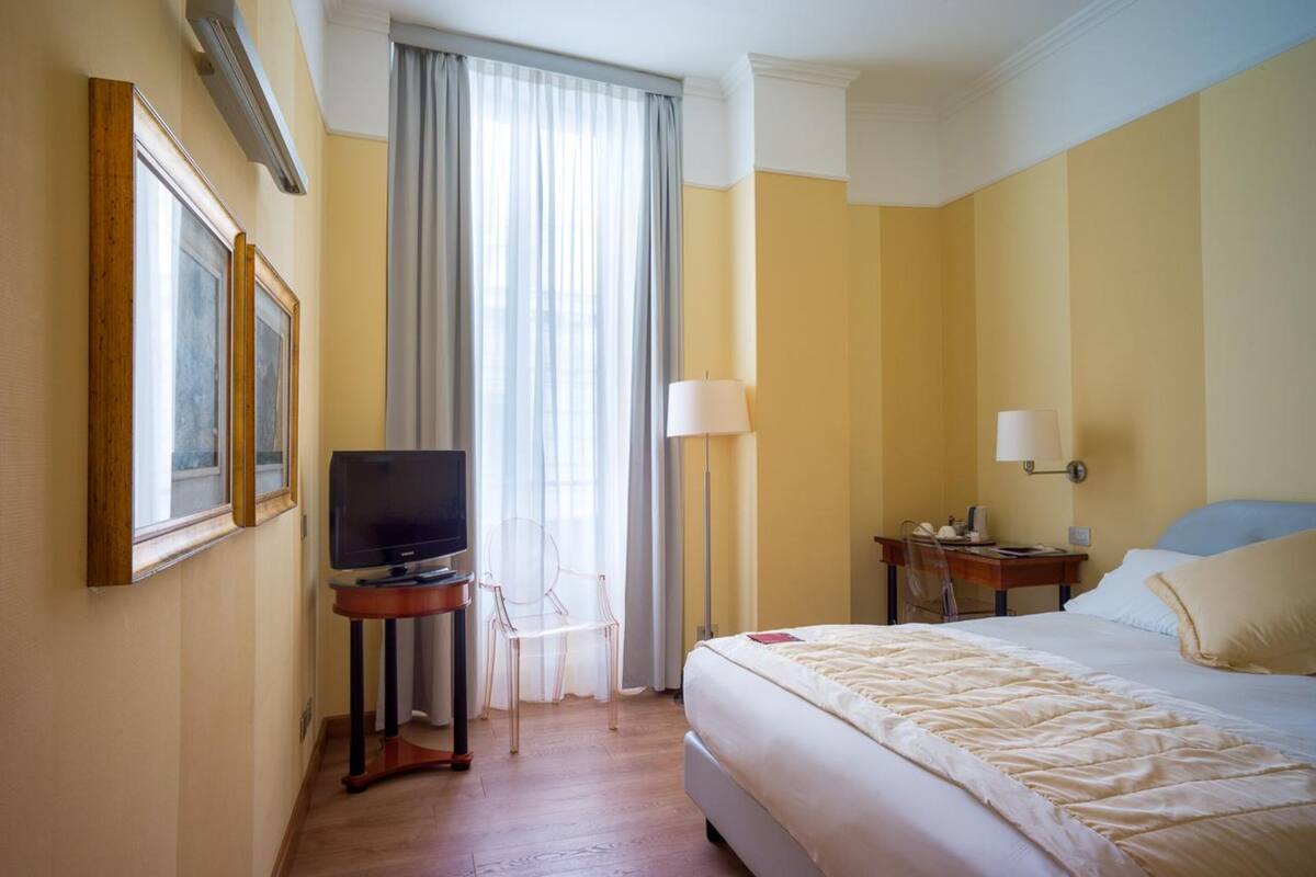 Une chambre d’hôtel avec un lit, une télévision, un bureau et une chaise.