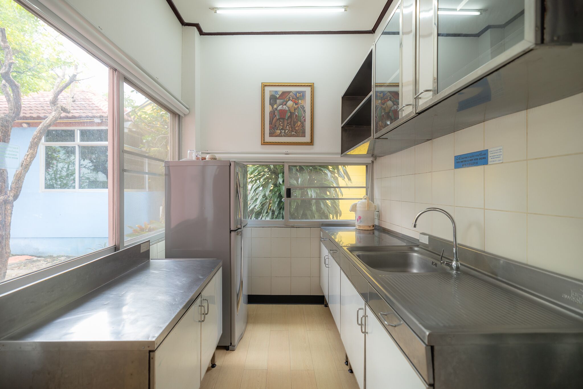 A compact kitchen with stainless steel appliances, a large window, and a tiled backsplash.
