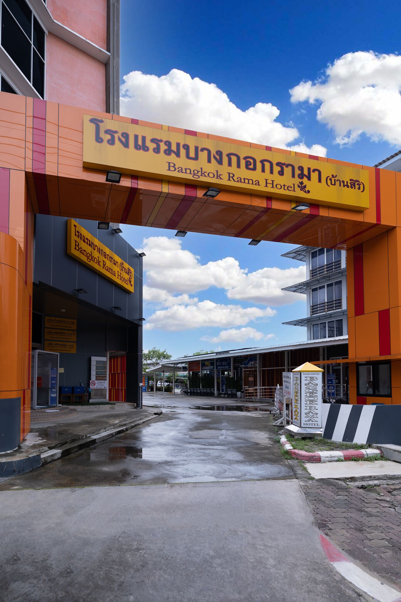 Der Eingang zum Bangkok Rama Hotel bei blauem Himmel und Wolken im Hintergrund.