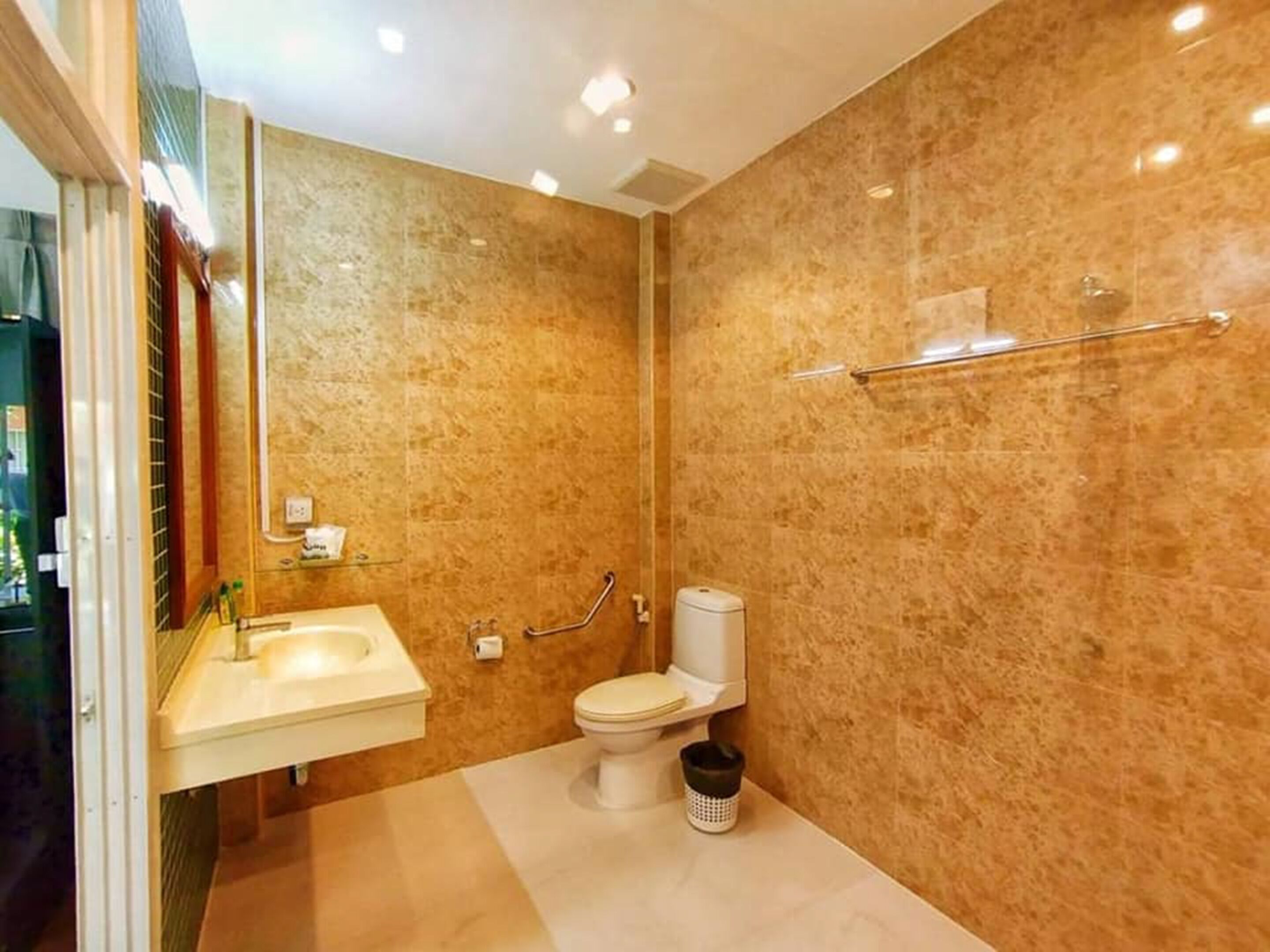 A bathroom with a marble wall, a white sink, a toilet, and a bidet.
