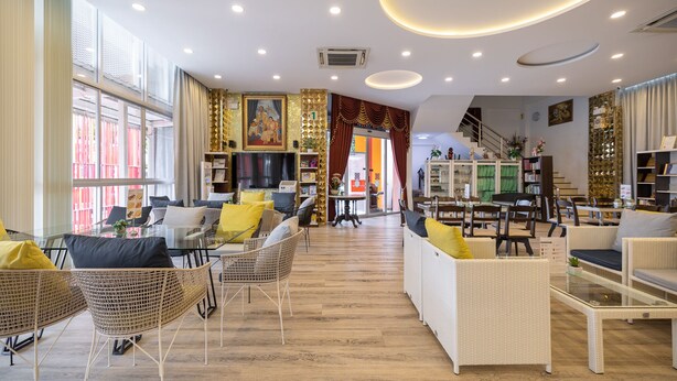 A spacious hotel lobby with wicker furniture, a staircase, and a view of the outside. - Bangkok Rama Hotel (Bangkok)