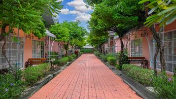Stroll through lush gardens, lined with traditional architecture and inviting benches, leading to a serene destination.