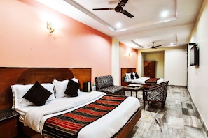 A hotel room with a bed, two chairs, a small table, and a ceiling fan.