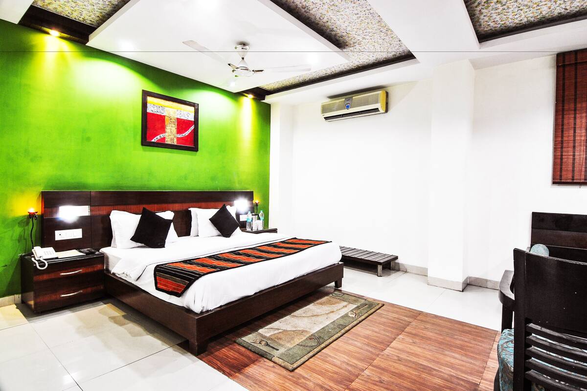 A modern hotel room with a large bed, a nightstand, a desk, and a chair.
