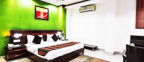 A modern hotel room with a large bed, a nightstand, a desk, and a chair.
