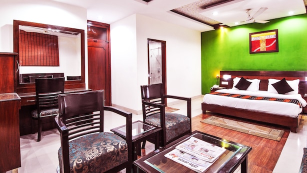 A hotel room with a bed, a desk, and two chairs. - Hotel Chand Palace (New Delhi)