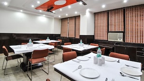 A conference room with tables set for dining, equipped with water bottles, and a ceiling fan. - Hotel Chand Palace (New Delhi)